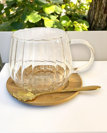 Glastasse mit Bambusuntersetzer und goldenem Löffel