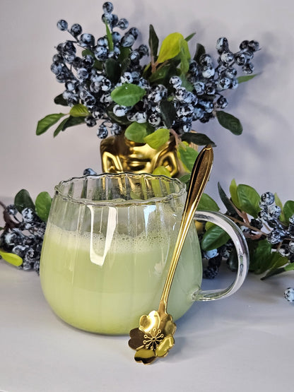 Glastasse mit Bambusuntersetzer und goldenem Löffel