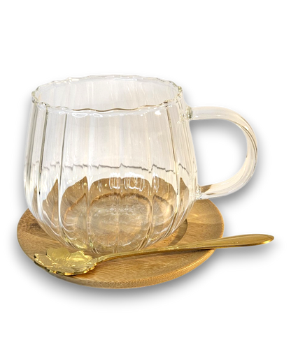 Glastasse mit Bambusuntersetzer und goldenem Löffel