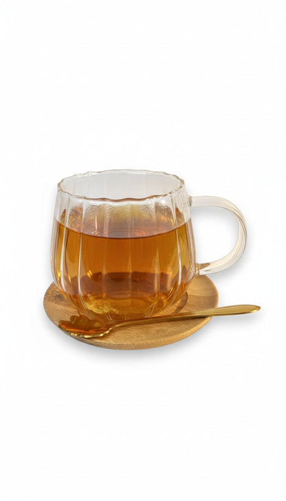 Glastasse mit Bambusuntersetzer und goldenem Löffel